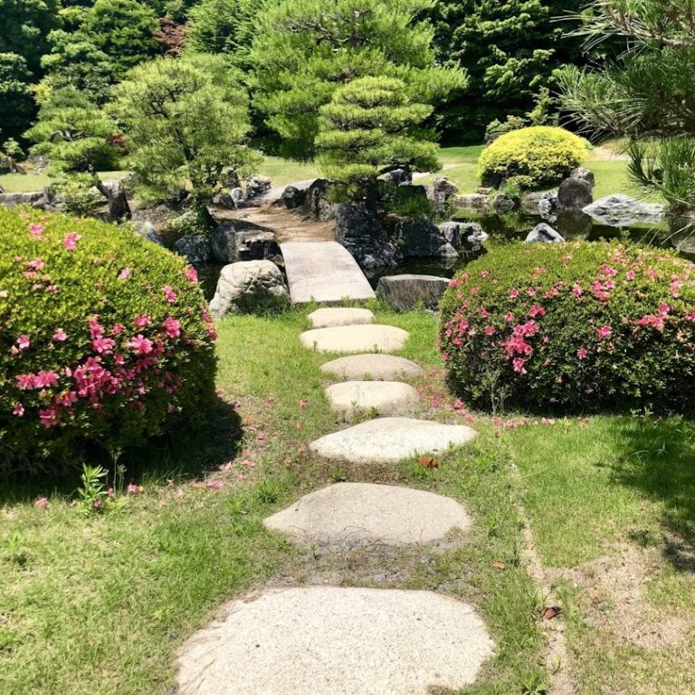 Vibrant flower beds with red, white, and purple blooms, surrounded by lush green grass.